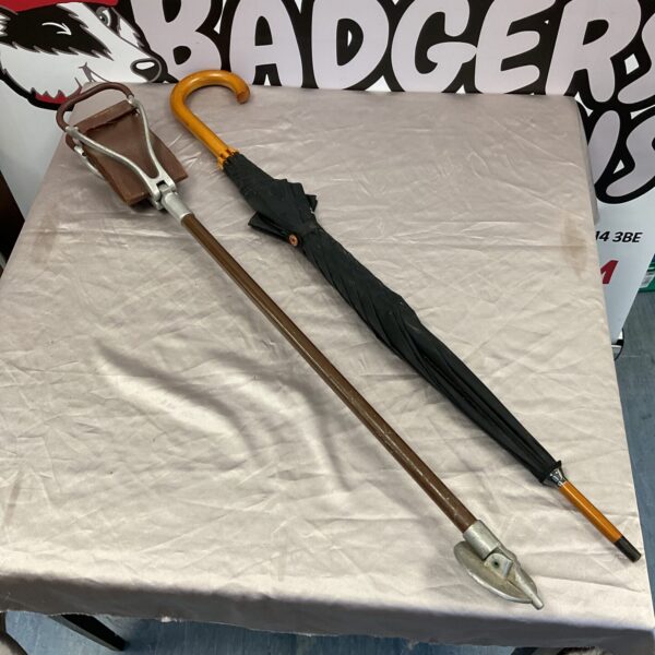Vintage shooting stick umbrella with wooden handle and dark canopy.