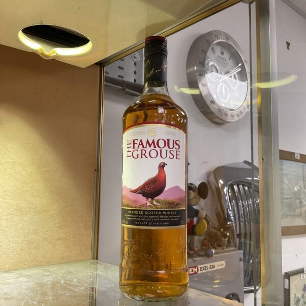 Sealed 1-litre bottle of Famous Grouse Scotch whisky on display.