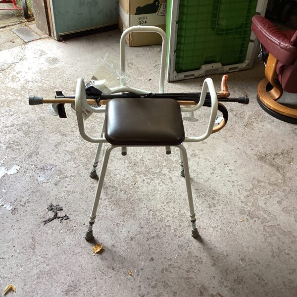 Adjustable height walking frame with padded seat for mobility assistance.