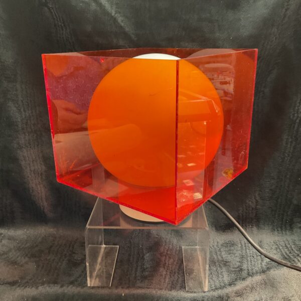 Vintage 1960s retro acrylic cube lamp with a red hue.