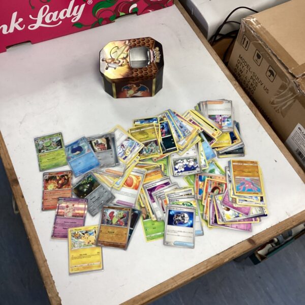 Pokemon card lot with holographic cards and a storage tin.
