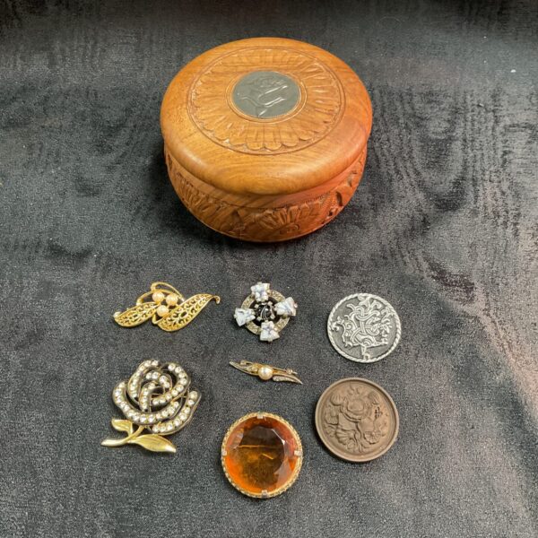 Wooden trinket box with a collection of brooches inc Scottish pewter and ceramic