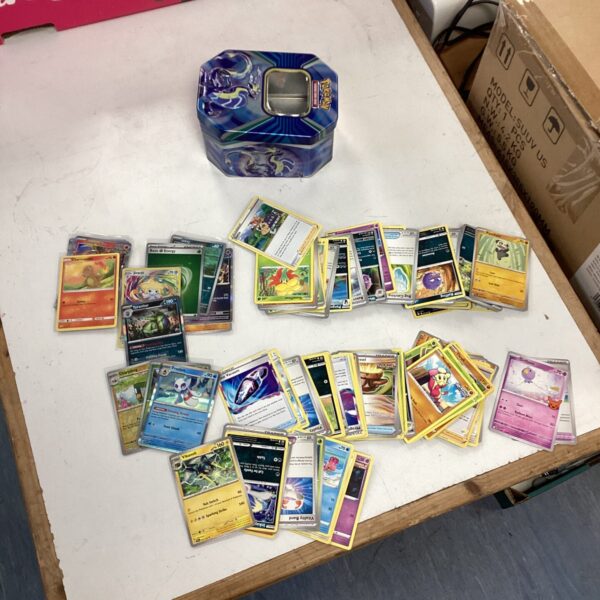 Pokemon card lot with holographic cards and storage tin.