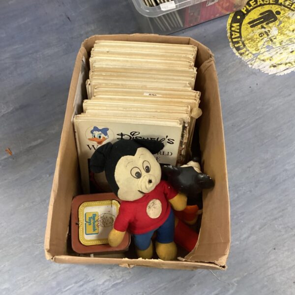 Vintage Disney books and a plush Mickey Mouse toy in a box.