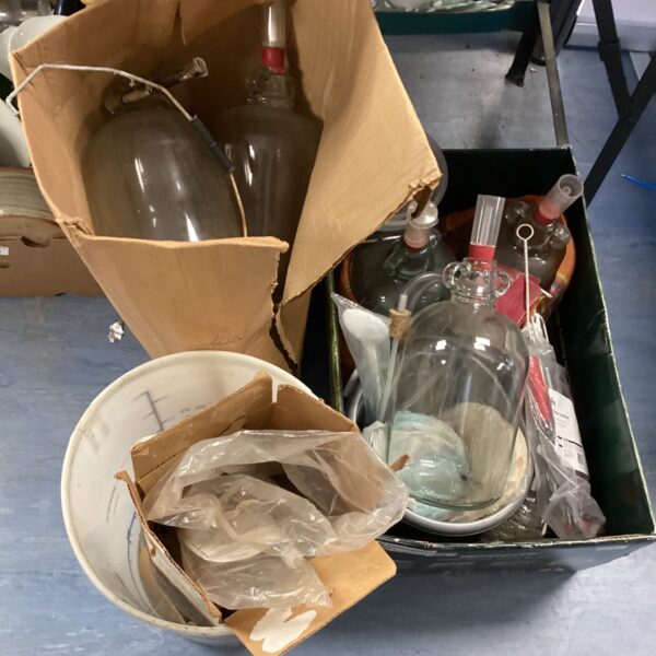 Lot of vintage wine making equipment including glass carboys and bottles.