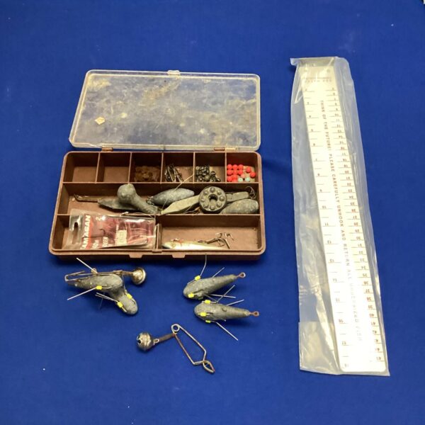 Assorted sea fishing tackle box with lead weights and lures.