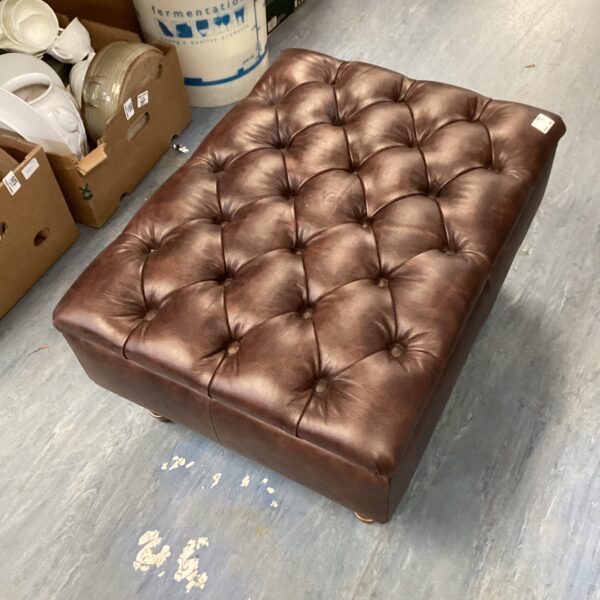 Vintage brown leather footrest with button tufting.
