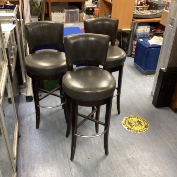 Three vintage Morgan leather bar stools with dark wood frames.