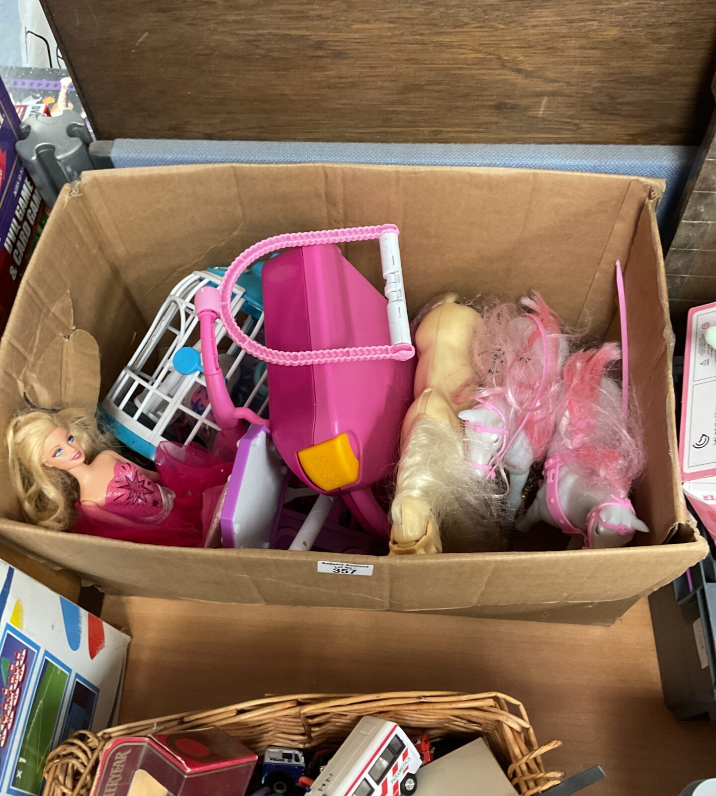 Box containing barbie dolls with a accessories and horses