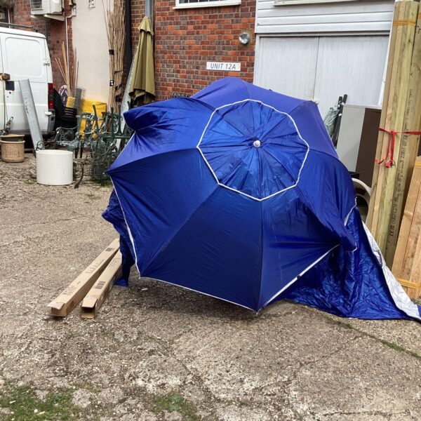 Two large blue beach parasols in a garden setting.
