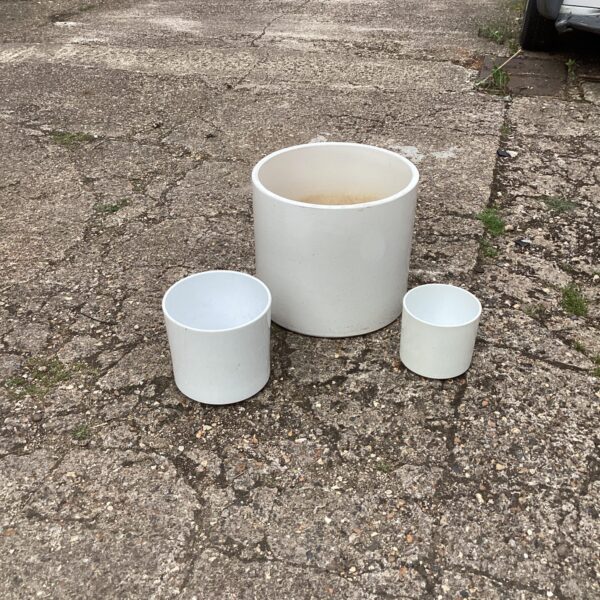 Three ceramic garden planters in a garden setting.