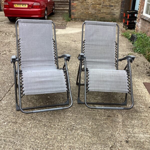 Two folding garden recliner chairs in a garden setting.