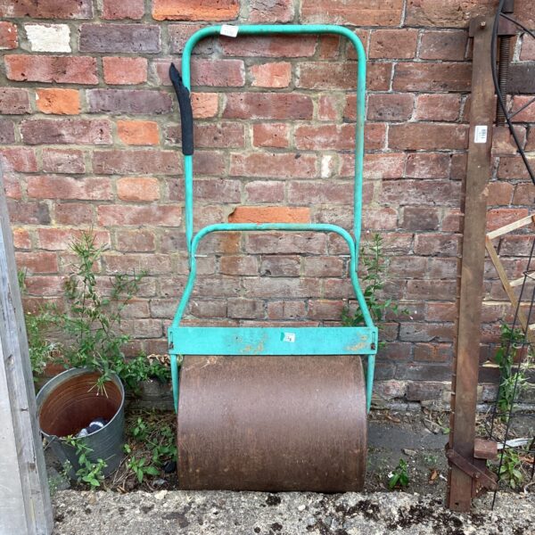 Vintage metal garden roller for lawn maintenance and soil consolidation.