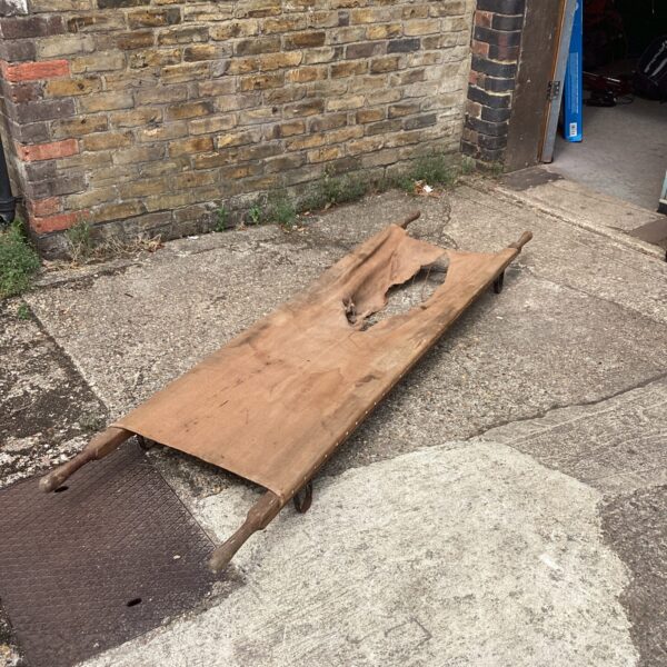 Vintage WW2 stretcher made of canvas and wood, showing signs of age.