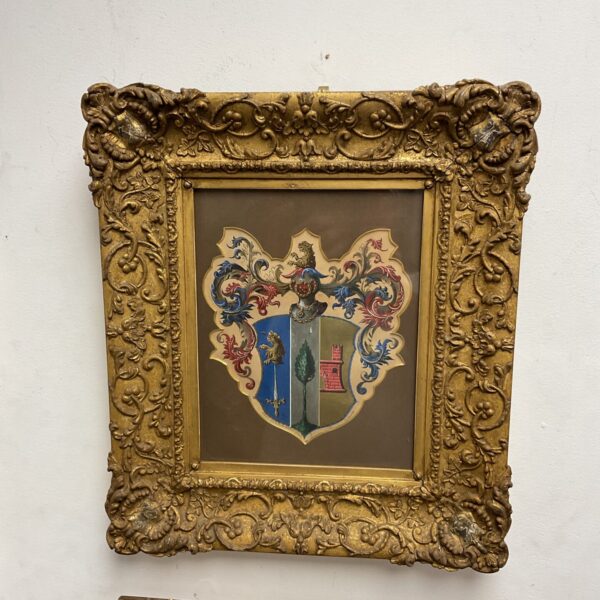 Antique oil painting of a family crest in a gilt frame.