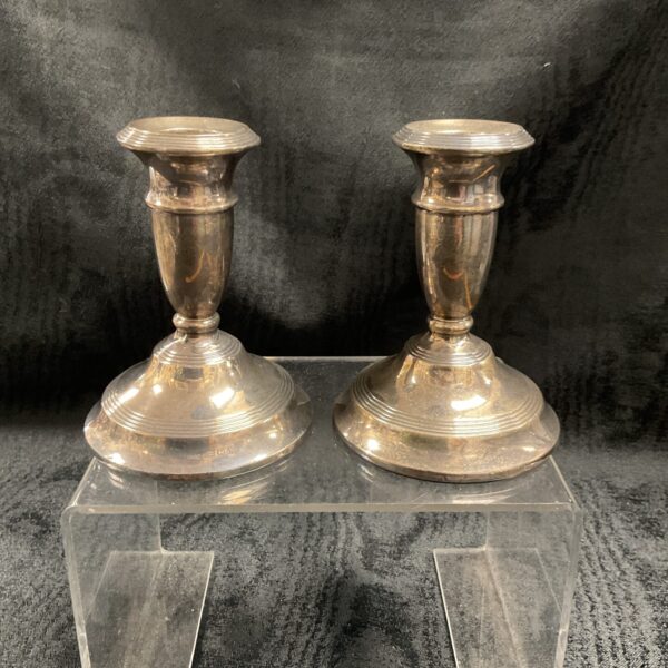 Pair of antique silver candlesticks on a clear stand.