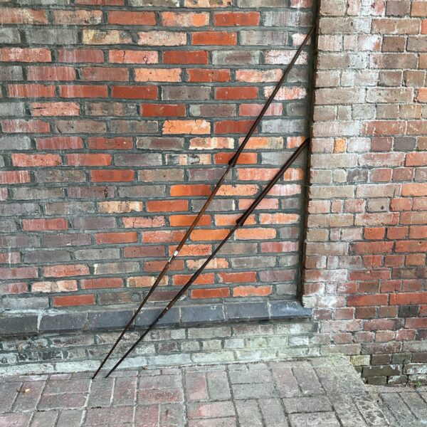 Antique African lion hunting spears leaning against a brick wall.
