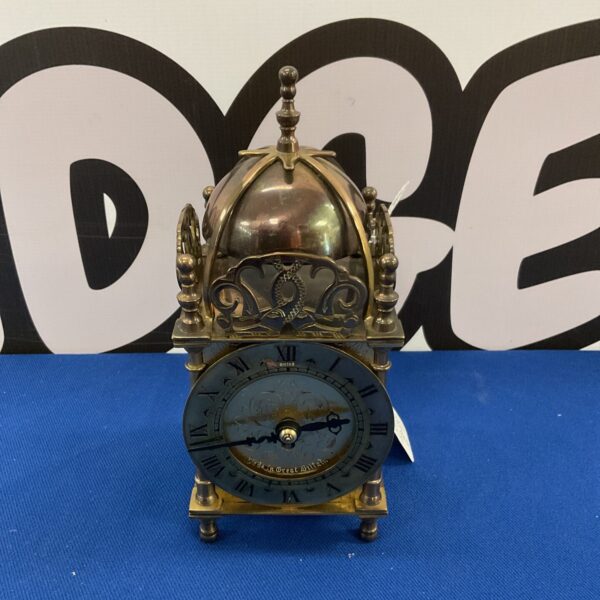 Vintage brass lantern clock with Roman numeral face.