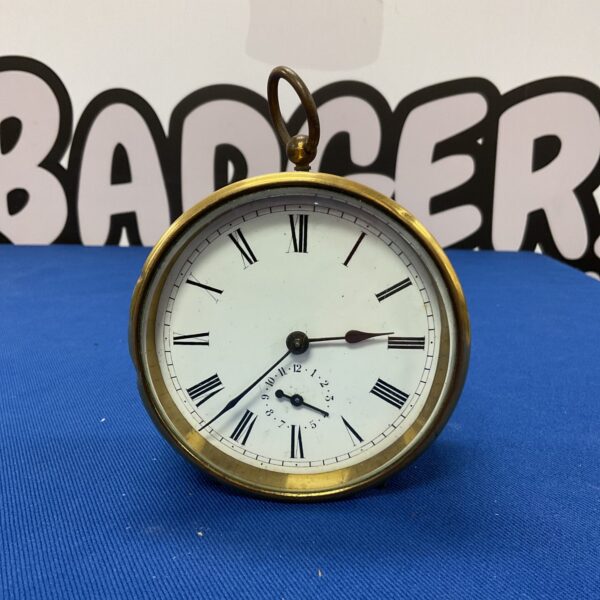 Antique brass drum clock with white enamel face and Roman numerals.
