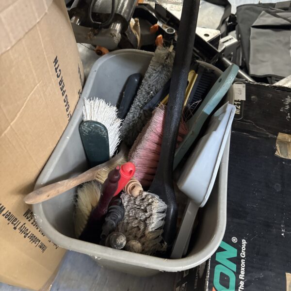 Assorted dustpans and brushes in a bucket for cleaning.