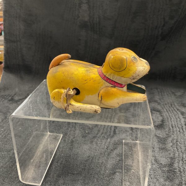 Vintage tin clockwork somersault dog toy, side view.