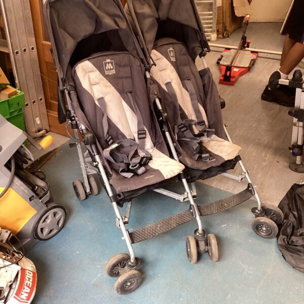 Side view of a vintage Maclaren twin pushchair.