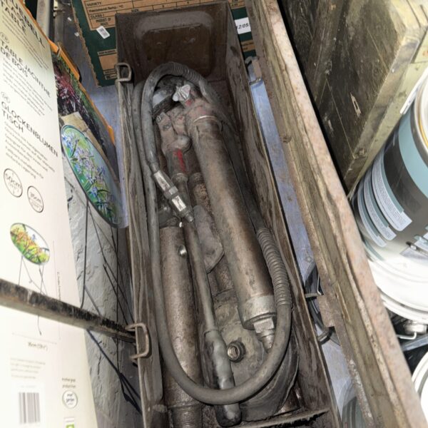 Vintage air ram in metal ammo crate, industrial pneumatic tool.