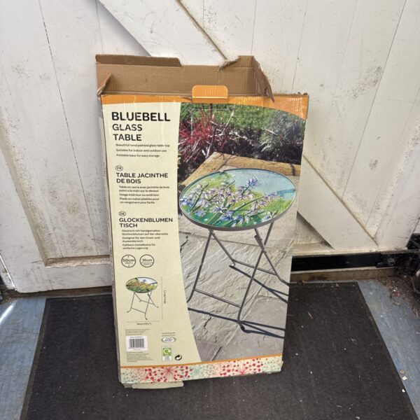 Bluebell folding garden table with painted glass top in outdoor setting.