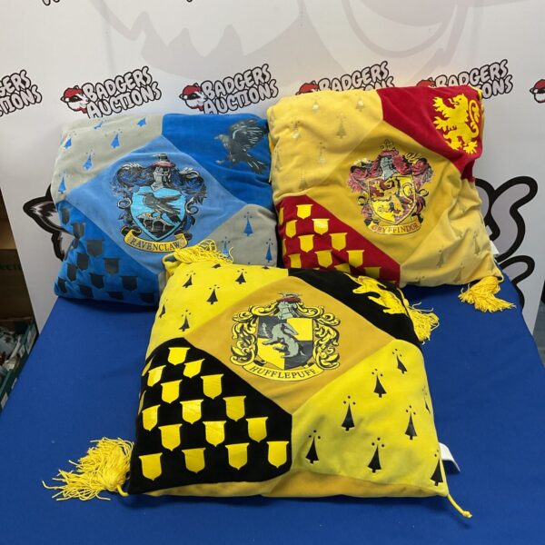 Harry Potter cushions featuring Gryffindor, Hufflepuff, and Ravenclaw house crests.