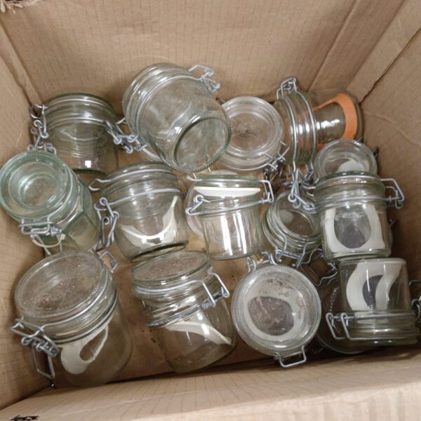 Vintage glass preserve jars with metal clasps in a cardboard box.