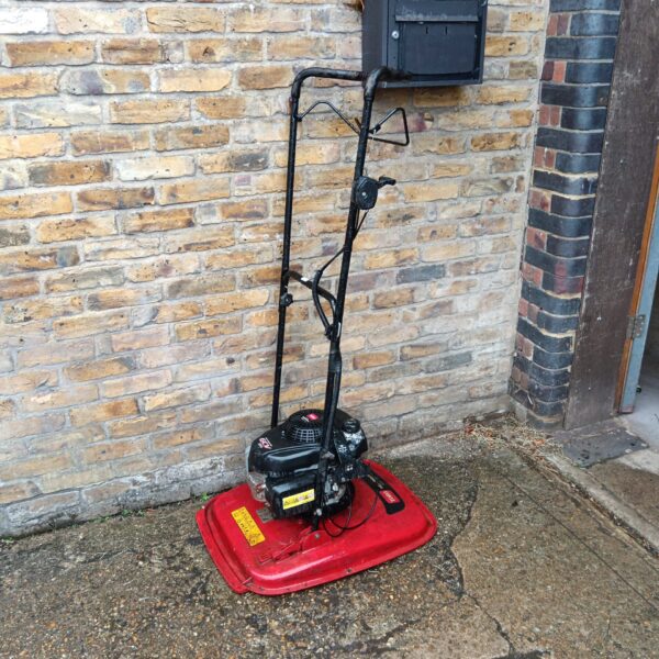 Red Toro Hoverpro lawnmower in a garden setting.