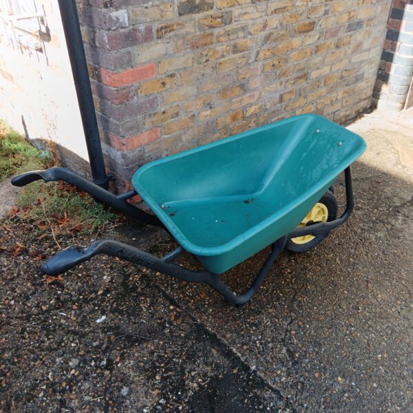 Green Lasher wheelbarrow in a garden setting.