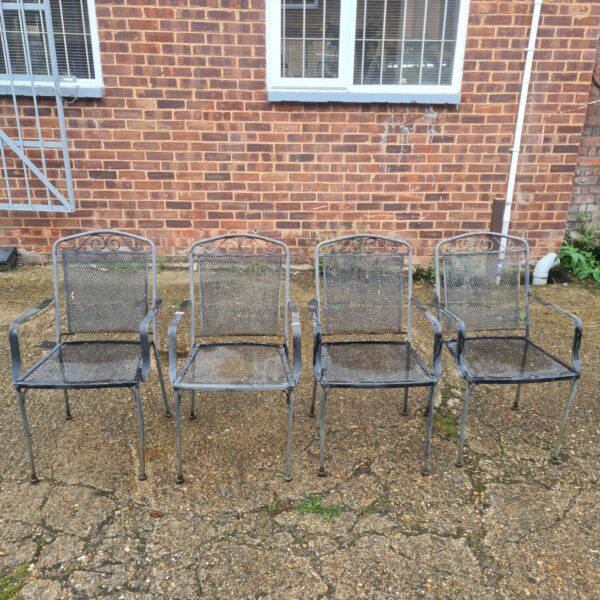 Set of four vintage wrought iron garden chairs in a garden.