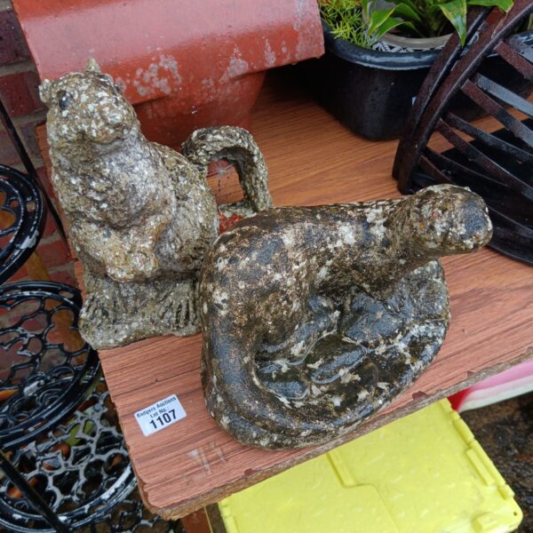 Weathered concrete garden squirrel and otter ornaments for outdoor display.