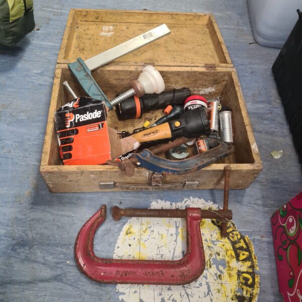 Mixed tool lot in wooden box with Paslode nail gun visible.