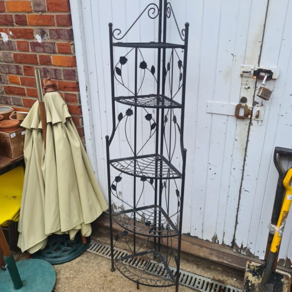 Vintage cast iron tiered plant stand in a garden setting.