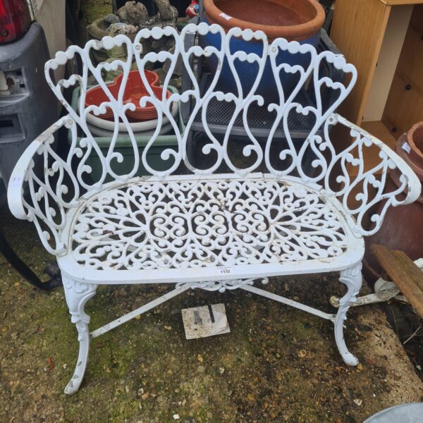 Ornate vintage cast iron garden bench in a garden setting.