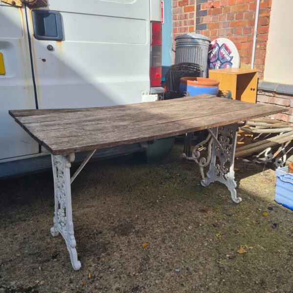 Vintage garden table with weathered wood and cast iron ends.