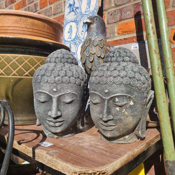 Weathered stone Buddha heads, a pair of garden statues.
