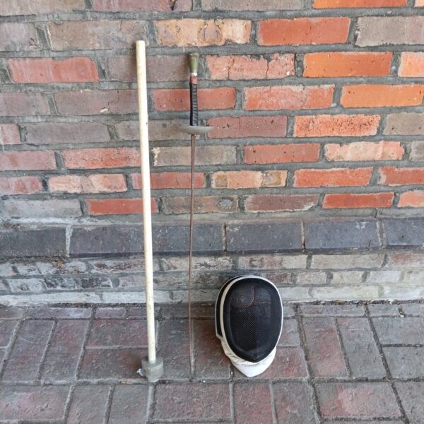 Vintage fencing set with foil and protective mask for sports practice.