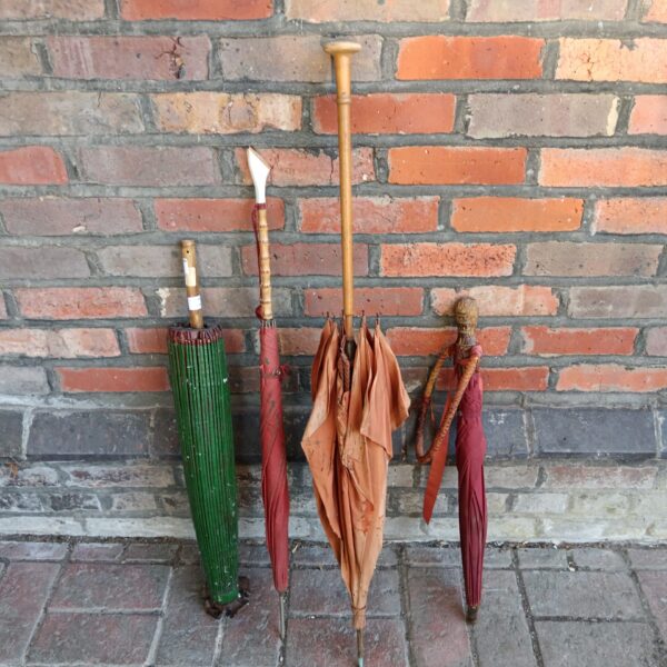 Group of four vintage umbrellas against a brick wall.