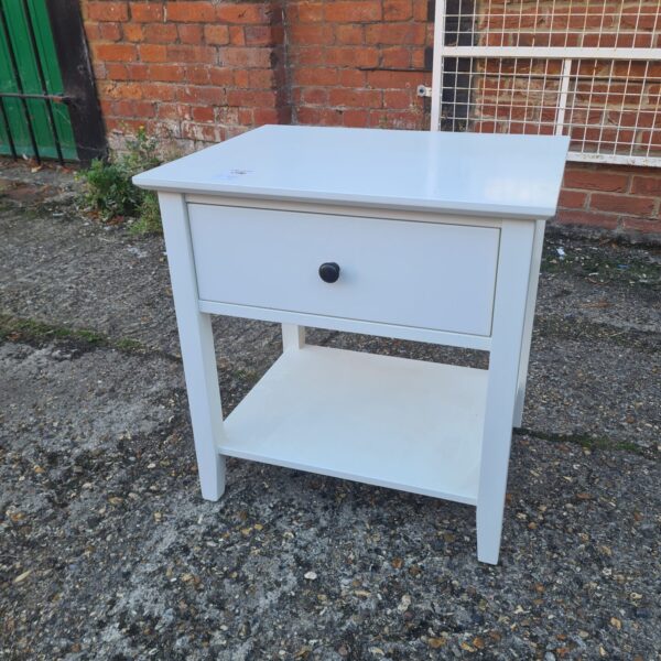 Small white bedside table with a drawer and shelf.