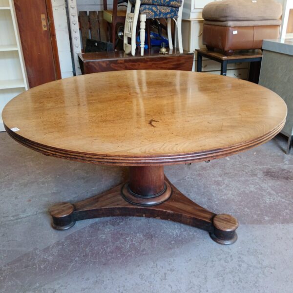 Large antique round oak dining table with pedestal base.
