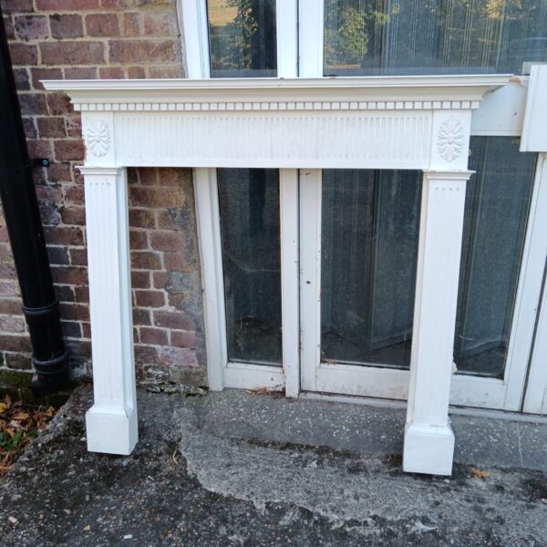 White vintage fireplace surround with fluted columns.