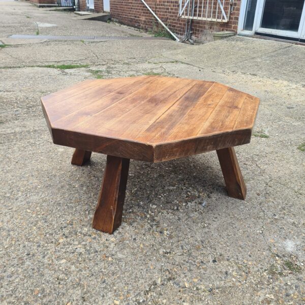 Solid oak brutalist coffee table with hexagonal top and angled legs.