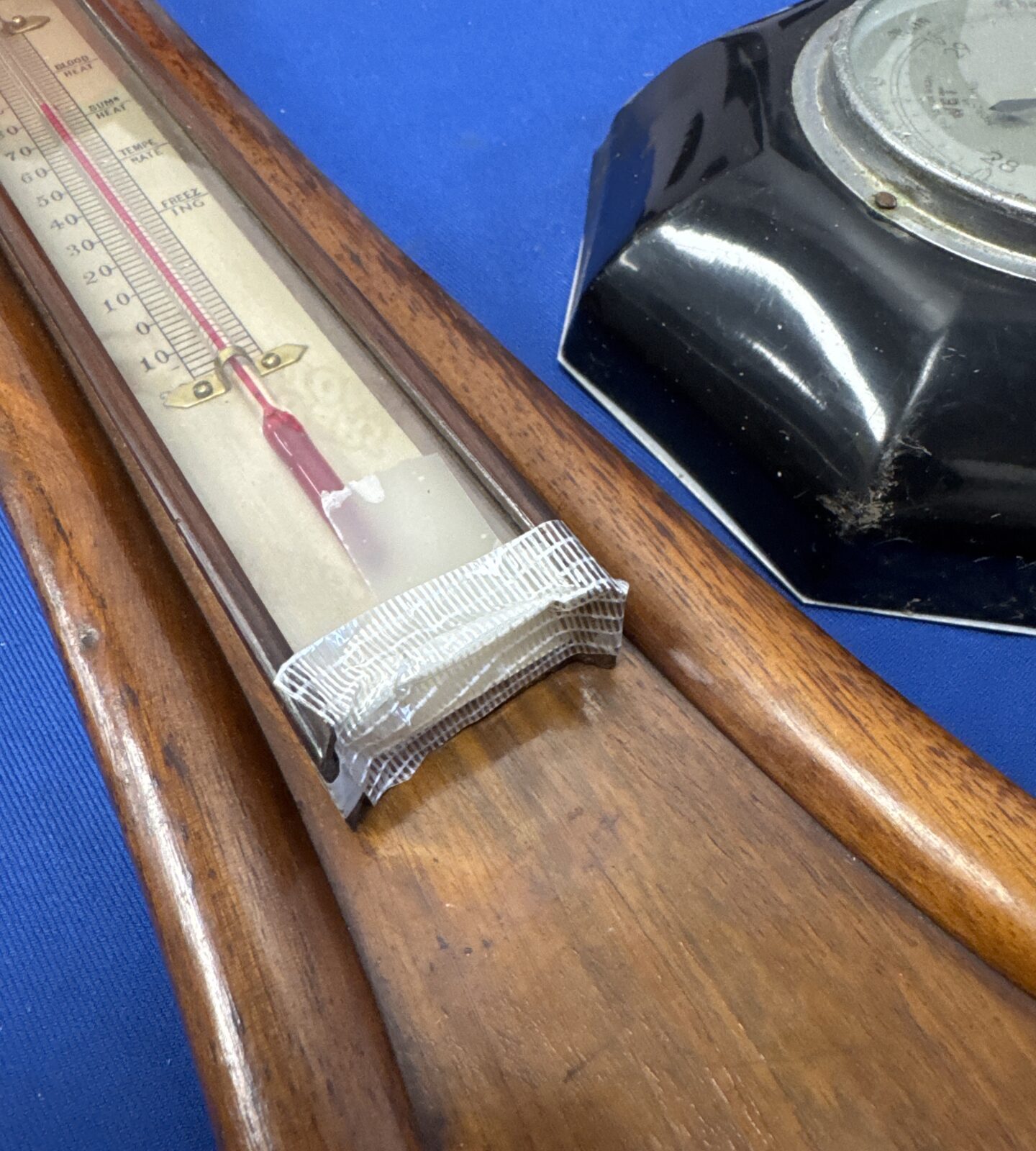 Close-up of a vintage barometer's thermometer with damage.