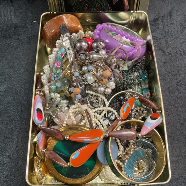 Vintage costume jewellery lot in a tin, assorted necklaces and brooches.