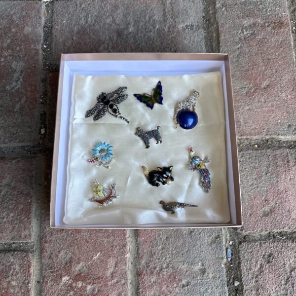 Vintage enamel brooch collection on a tray.
