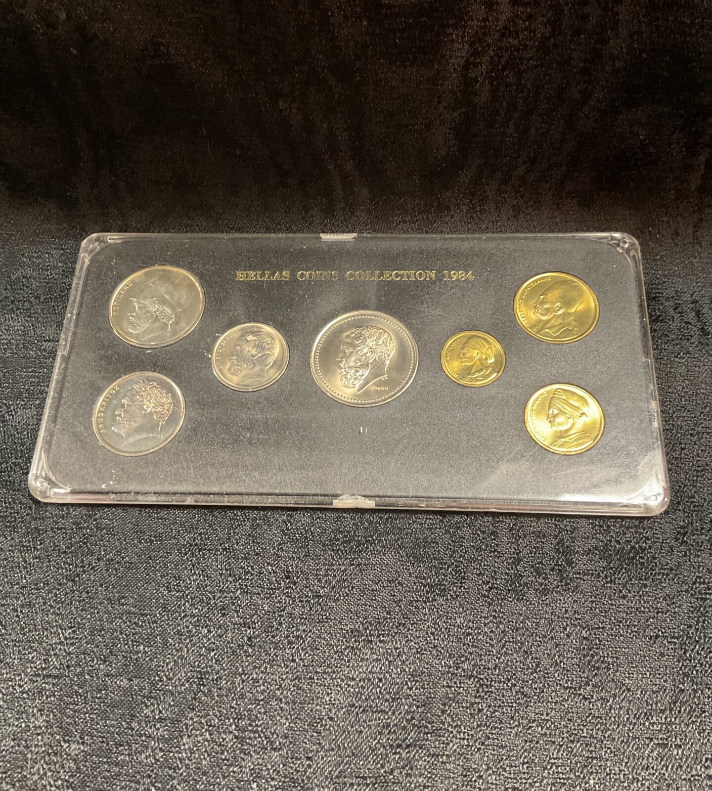 Front view of the 1984 Hellas coin collection in a clear case.