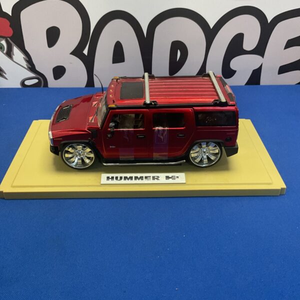 Red Jada Toys Hummer H2 diecast model on display stand.
